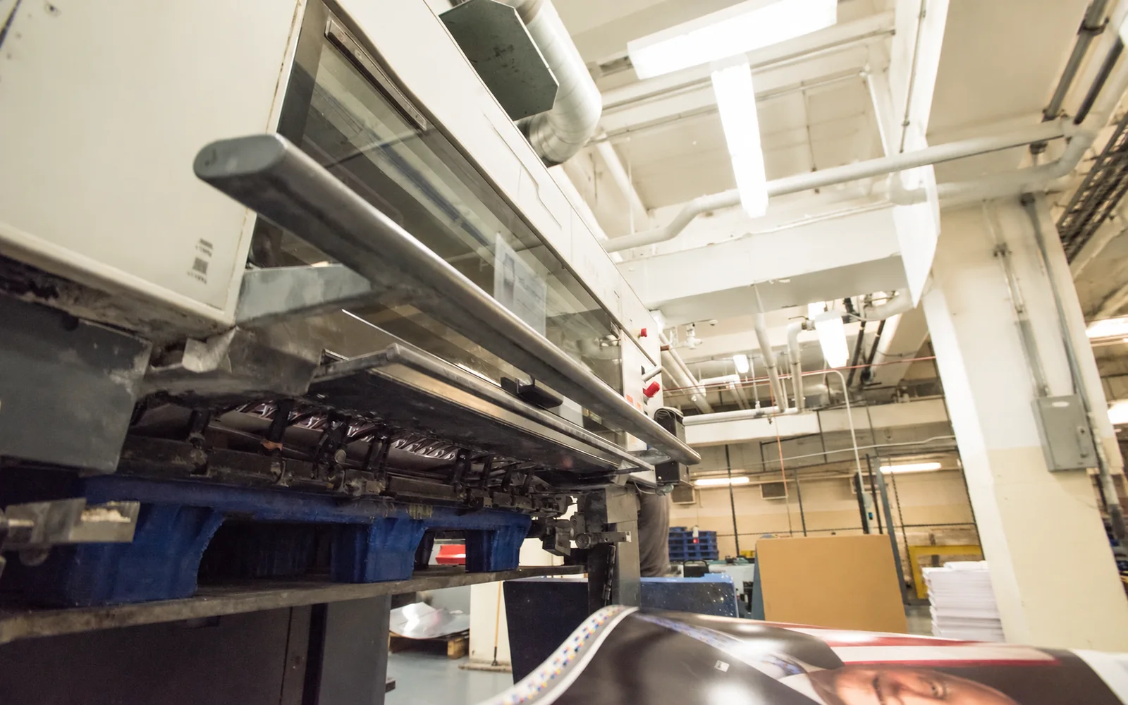 Press operator checking fresh print color under calibrated inspection lighting